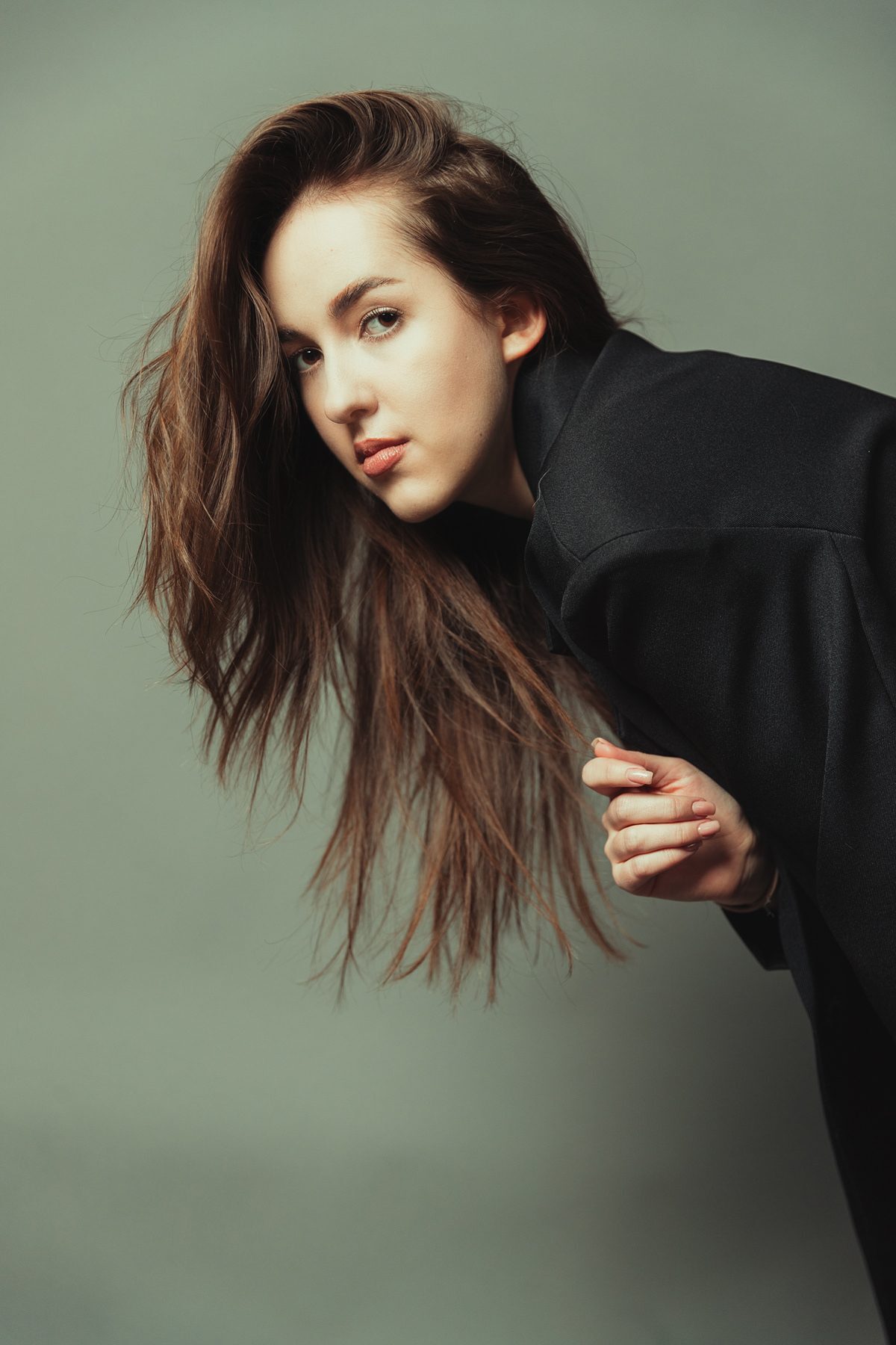 A model tipped backwards over a moulded chair in a grey studio, legs in the air