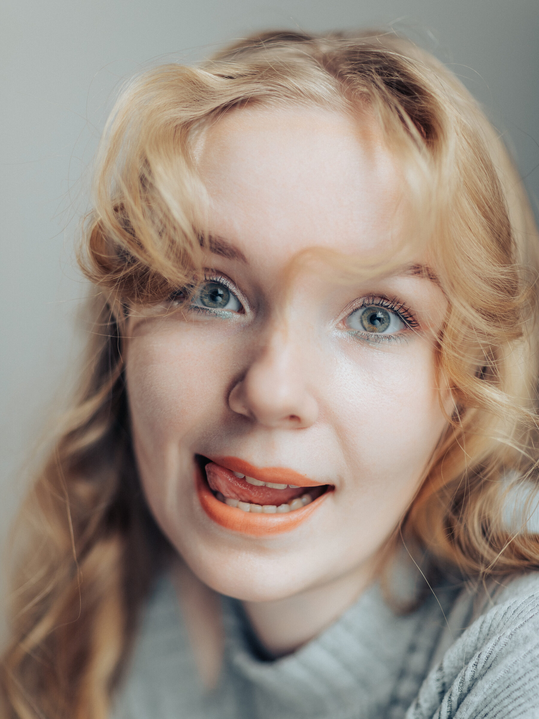 Close-up of a woman with green eyes grinning with her tongue between her teeth